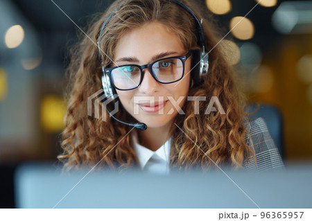 Call center agent with headset working on support hotline in modern office. Video conference. 96365957