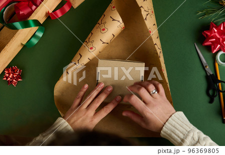 Top view woman packing presents for Christmas or New Year's event. Boxing Day. Xmas holidays. Handwork art. Creativity Top view woman packing presents for Christmas or New Year's event. Boxing Day. Xmas holidays. Handwork art. Creativity 96369805