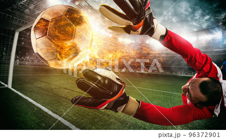 Close up of a soccer scene at night match with a goalkeeper trying to catch a fiery ball 96372901