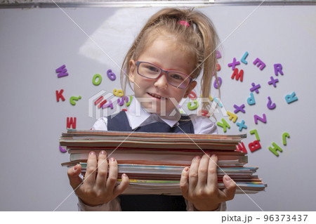 optimistic Little beautiful smiling girl holding books 96373437