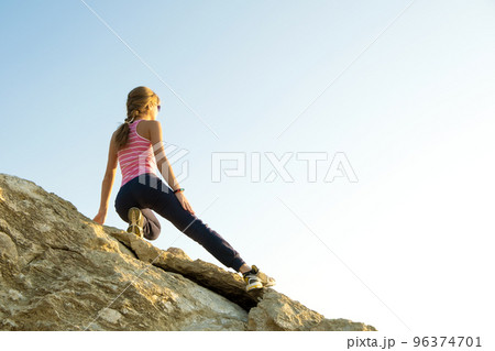 Woman hiker climbing steep big rock on a sunny day. Young female climber overcomes difficult climbing route. Active recreation in nature concept. 96374701