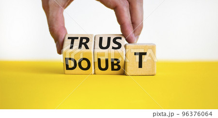 Trust or doubt symbol. Businessman turns wooden cubes and changes the word doubt to trust. Beautiful yellow table, white background, copy space. Business and trust or doubt concept. 96376064