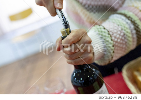 Corkscrew. Came. Time to open the bottle of red wine with the corkscrew. Woman's hands holding the bottle while opening the cork. Horizontal photography. 96376238