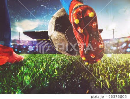 Football scene at night match with close up of a soccer shoe hitting the ball with power Football scene at night match with close up of a soccer shoe hitting the ball with power 96376806