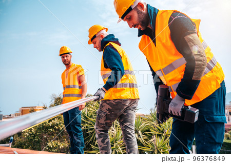 Team of technical workers work on the roof of a house 96376849