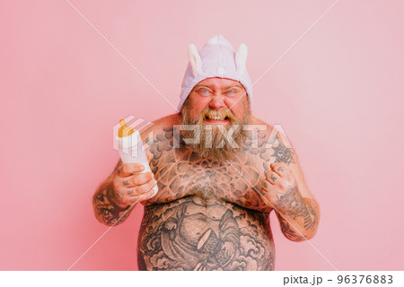 Funny man with beard in yoga position on studio pink background