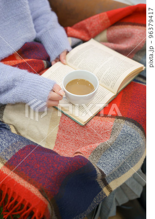 カフェオレを飲みながら読書する女性の手元 96379417