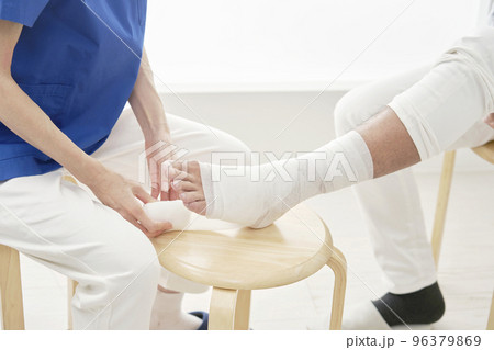 患者の足首に包帯を巻く看護師　顔無し 96379869