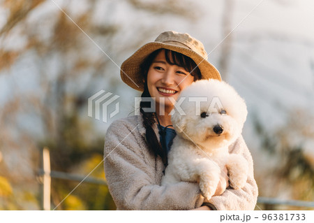 秋冬のキャンプ場で愛犬を抱くキャンパーのアジア人女性(ビジョンフリーゼ) 秋冬のキャンプ場で愛犬を抱くキャンパーのアジア人女性(ビジョンフリーゼ) 96381733