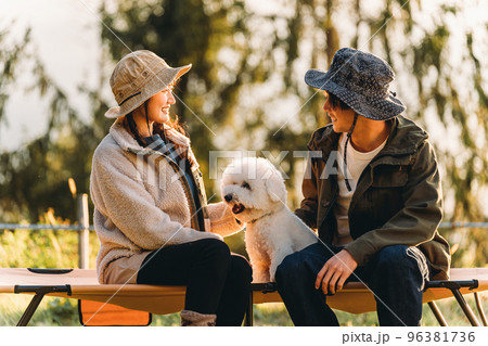 愛犬と秋冬キャンプを楽しむキャンパーのアジア人男女（ビジョンフリーゼ） 96381736