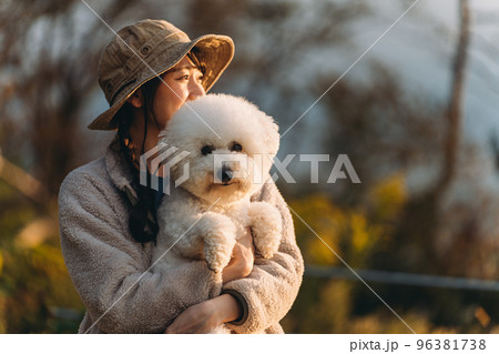 キャンプ場で愛犬を抱くキャンパーのアジア人女性（ビジョンフリーゼ） 96381738