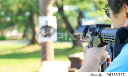Air soft gun holding by man aiming at the blur shooting target in the shooting range, soft and selective focus on the gun Air soft gun holding by man aiming at the blur shooting target in the shooting range, soft and selective focus on the gun 96383577