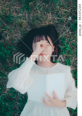 寝そべって本を読む若い女性の写真 96385284