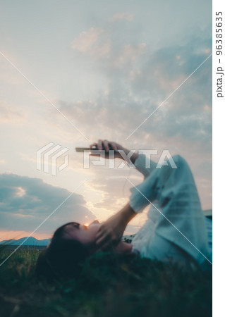 寝そべって音楽を聴く若い女性の写真 96385635