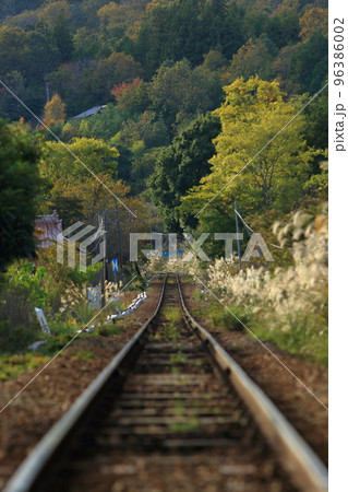 紅葉の木々に向かって伸びる線路 96386002