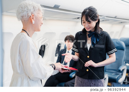 乗客に座席の案内をするキャビンアテンダント 96392944