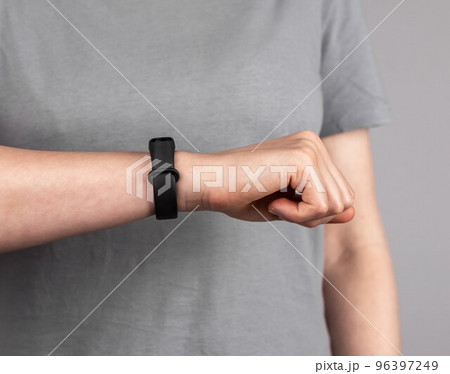 Woman looking at fitness tracker for checking physical activity results. Female with band at wrist for walking steps, running distance, heart rate or sleep patterns monitoring. 96397249