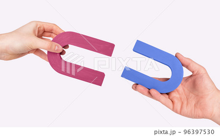 Magnets in man and woman hands. Love and relationship concept. Symbol of magnetic attraction between lovers Magnets in man and woman hands. Love and relationship concept. Symbol of magnetic attraction between lovers 96397530