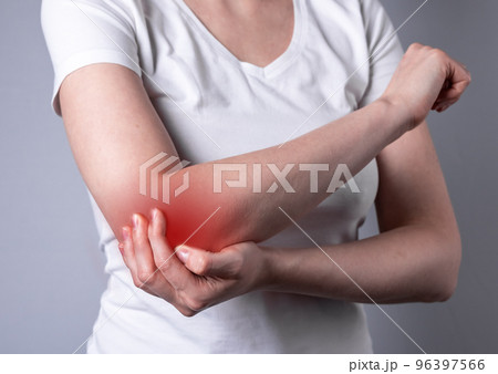 Woman suffering from elbow pain and holding painful hand with red point closeup. Hand injury. Health problems, medicine, treatment concept. 96397566