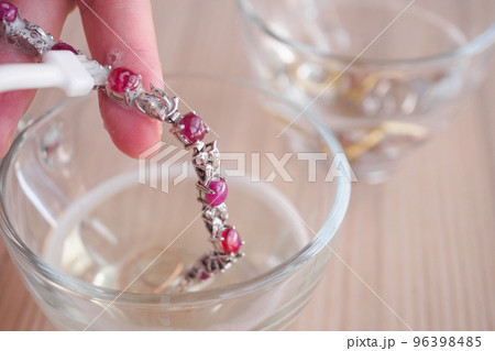 Jeweller hand cleaning and polishing vintage jewelry red ruby bracelet closeup Jeweller hand cleaning and polishing vintage jewelry red ruby bracelet closeup 96398485