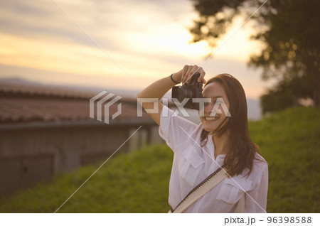 Young woman enjoying when her using camera ,golden hour in background 96398588