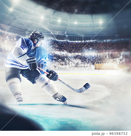 The arena of a hockey rink, a hockey player hits a hockey stick with a swing on the puck The arena of a hockey rink, a hockey player hits a hockey stick with a swing on the puck 96398752