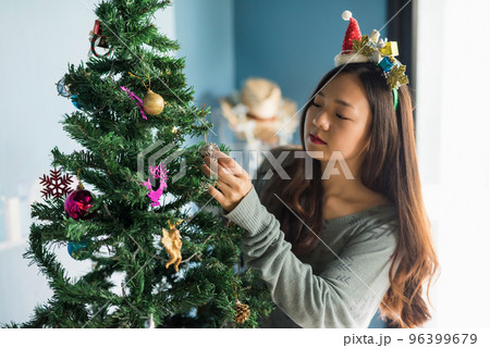 Asian young woman decorate silver pine cone to christmas tree 96399679