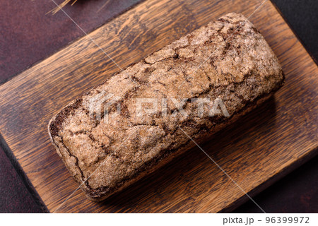A loaf of brown bread with grains of cereals on a wooden cutting board A loaf of brown bread with grains of cereals on a wooden cutting board 96399972