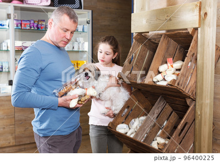girl with father choosing dog treats 96400225