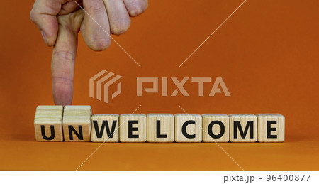 Welcome or unwelcome symbol. Businessman turns wooden cubes and changes the word unwelcome to welcome. Beautiful orange table, orange background. Welcome or unwelcome and business concept. Copy space. Welcome or unwelcome symbol. Businessman turns wooden cubes and changes the word unwelcome to welcome. Beautiful orange table, orange background. Welcome or unwelcome and business concept. Copy space. 96400877