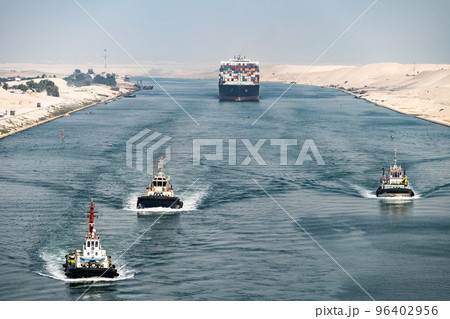 Huge cargo ships with pilot boats navigate by Suez Canal, Egypt. Concept of transportation and logistics  96402956