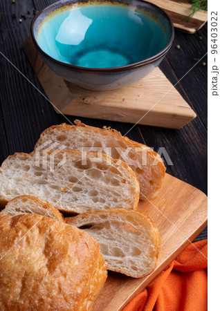 fresh ciabatta bread with blue bowl and ingredients served at dark wooden table. meditarranean cuisine. fresh ciabatta bread with blue bowl and ingredients served at dark wooden table. meditarranean cuisine. 96403022