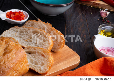 fresh ciabatta bread  with blue bowl and ingredients served at dark wooden table. meditarranean cuisine. close up 96403027