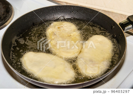 Woman frying pies in oil in a cast iron pan Woman frying pies in oil in a cast iron pan 96403297
