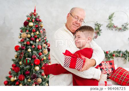 Grandson giving grandpa a Christmas present. Cute little boy is giving his father a gift and smiling. Grandson giving grandpa a Christmas present. Cute little boy is giving his father a gift and smiling. 96406725