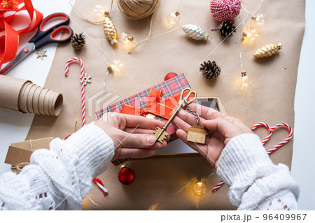 Key to house with keychain on cozy home in gift box with Christmas decor packaging. Pack present for New Year, Christmas. Building, project, moving to new house, mortgage, rent, purchase real estate Key to house with keychain on cozy home in gift box with Christmas decor packaging. Pack present for New Year, Christmas. Building, project, moving to new house, mortgage, rent, purchase real estate 96409967