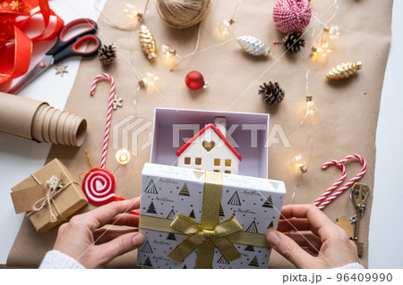 Key to house with keychain on cozy home in gift box with Christmas decor packaging. Pack present for New Year, Christmas. Building, project, moving to new house, mortgage, rent, purchase real estate 96409990