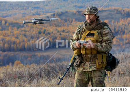 An artillery spotter or military observer launches a drone into the sky for reconnaissance in enemy territory. 96411910