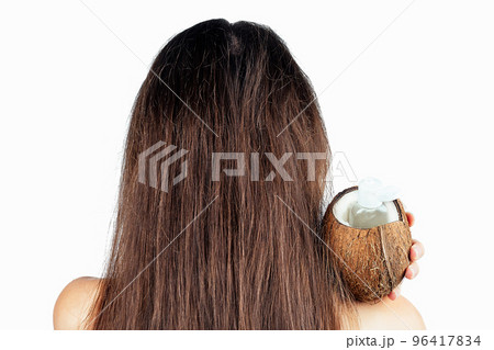 sexy nude indian woman applying coconut oil from the bottle and cap to dark brunette long hair in a hand on white isolate back view 96417834