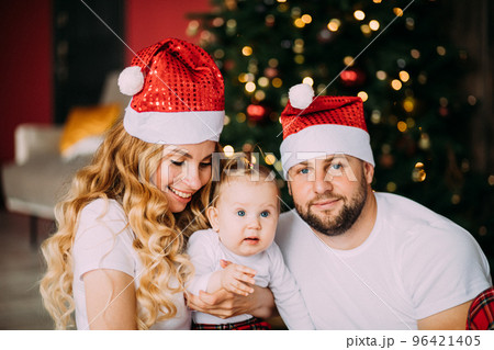 Happy father in Santa hat near his wife and baby Happy father in Santa hat near his wife and baby 96421405