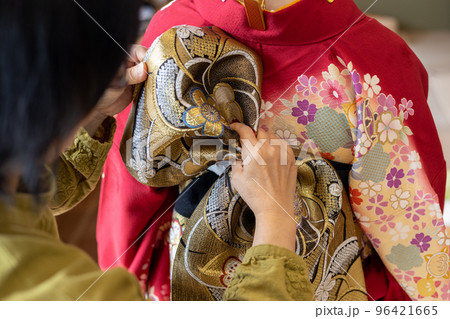 若い女性に振袖の着付けしているところ 96421665