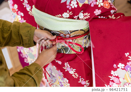 若い女性に振袖の着付けしているところ 96421751