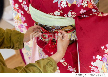 若い女性に振袖の着付けしているところ 96421756