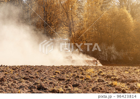 In the autumn, a farmer pulls harrows with a modern tractor and sows a field with beets. Sowing campaign on agricultural land during tillage. In the autumn, a farmer pulls harrows with a modern tractor and sows a field with beets. Sowing campaign on agricultural land during tillage. 96423814
