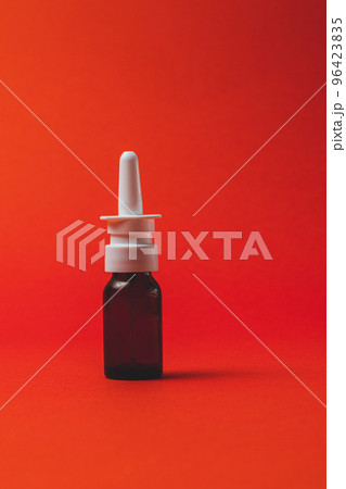 nasal spray in dark bottle with nozzle on red background. nasal spray in dark bottle with nozzle on red background. 96423835