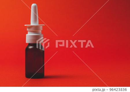 nasal spray in dark bottle with nozzle on red background. 96423836