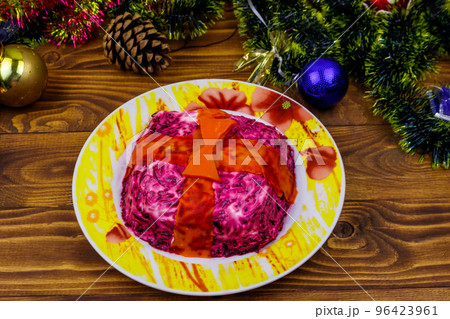 Traditional russian salad "Herring under a fur coat" (shuba) and Christmas decorations on wooden table. Salad made in a shape of gift box Traditional russian salad "Herring under a fur coat" (shuba) and Christmas decorations on wooden table. Salad made in a shape of gift box 96423961