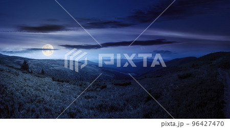 panoramic view in to valley. stunning landscape of carpathian mountains at night in summer. forested hills and grassy meadows beneath a bright blue sky in full moon light panoramic view in to valley. stunning landscape of carpathian mountains at night in summer. forested hills and grassy meadows beneath a bright blue sky in full moon light 96427470