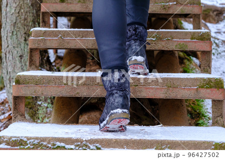 A woman climbs the stairs in winter. In winter, there is a risk of slipping on snowy stairs A woman climbs the stairs in winter. In winter, there is a risk of slipping on snowy stairs 96427502