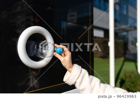 Woman uses a self service machine to receive used plastic bottles  96429963